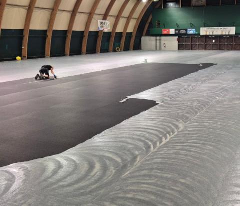 techniciens Idema effectuant la pose du nouveau sol sportif